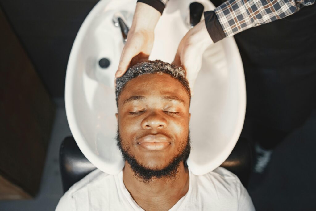 Man enjoying a relaxing hair wash at the barber shop, eyes closed and serene.