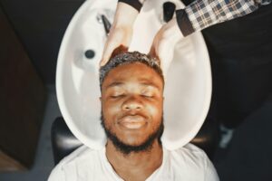 Man enjoying a relaxing hair wash at the barber shop, eyes closed and serene.